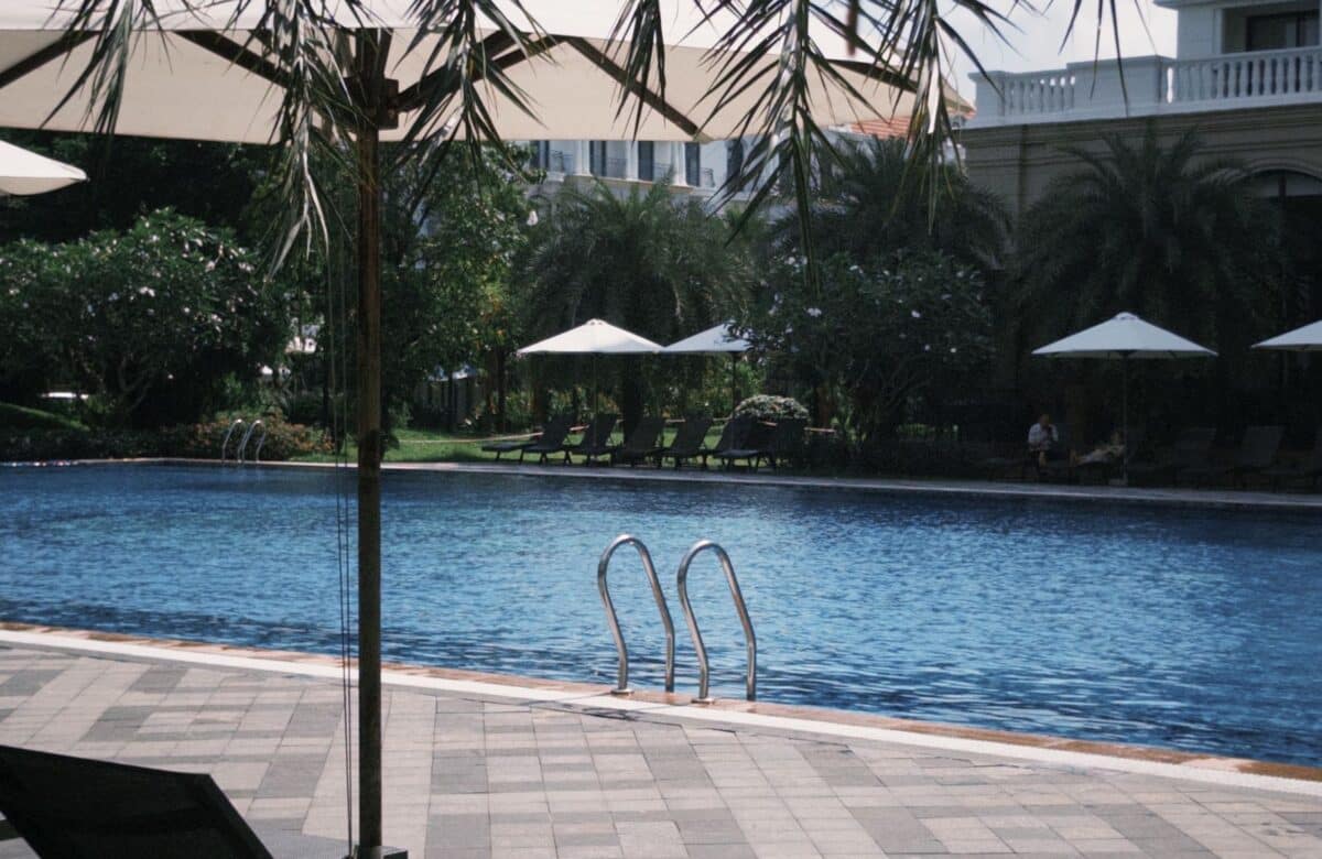 Clubhouse pool - LORDS OF THE LANDS Landscaped resort swimming pool with loungers and umbrellas beside a clubhouse — Lords of the Lands