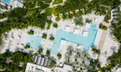 Aerial view of a resort clubhouse with a turquoise swimming pool surrounded by palms and landscaped gardens — Lords of the Lands