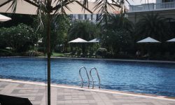 Landscaped resort swimming pool with loungers and umbrellas beside a clubhouse — Lords of the Lands